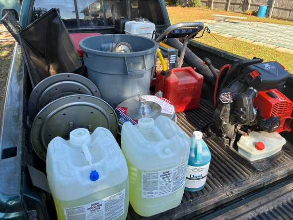Truck bed loaded with mower, trimmer and cleaning supplies